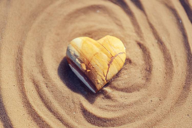 Heart shaped stone lying on rippled sand