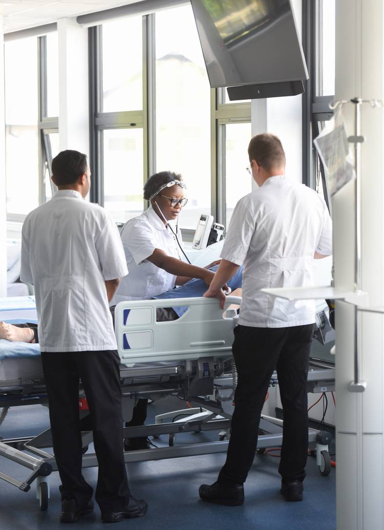 Students at a bedside in a stimulation ward