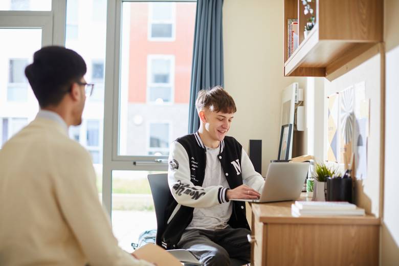 Students sitting at a desk in student accommodation
