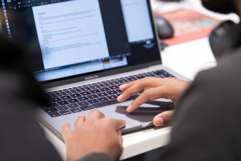 A close-up photo of hands typing at a laptop computer