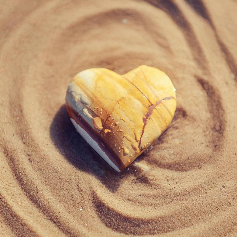 Heart shaped stone lying on rippled sand