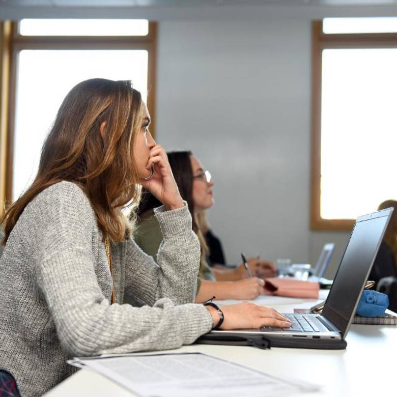 A student sitting in a seminar with a laptop