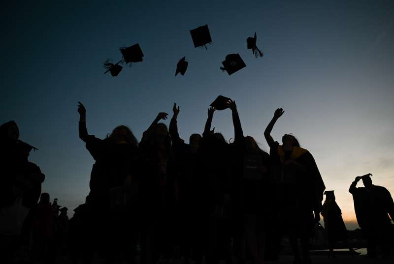 Graduation at sunset with students throwing their caps