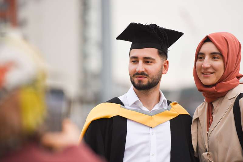 A student standing with a relative at graduation