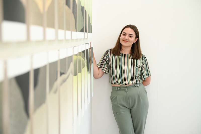 A student standing with their artwork