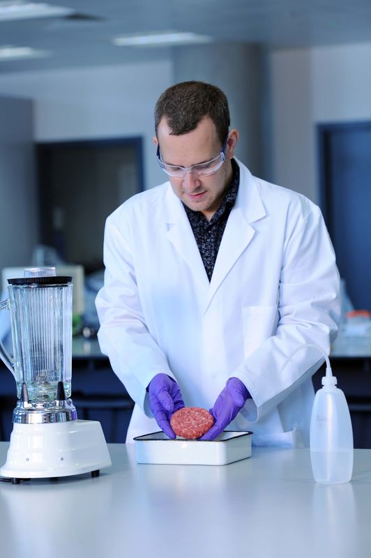 A lecturer handling minced meat in a lab