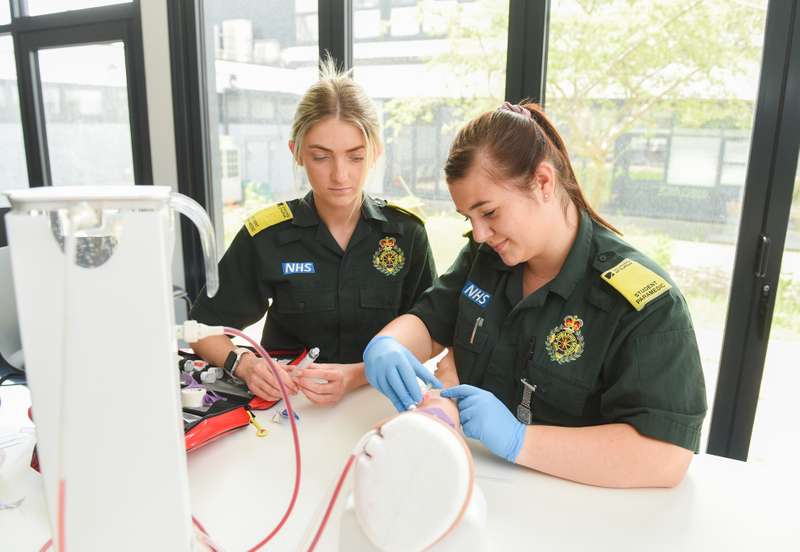 Two students using phlebotomy training equipment