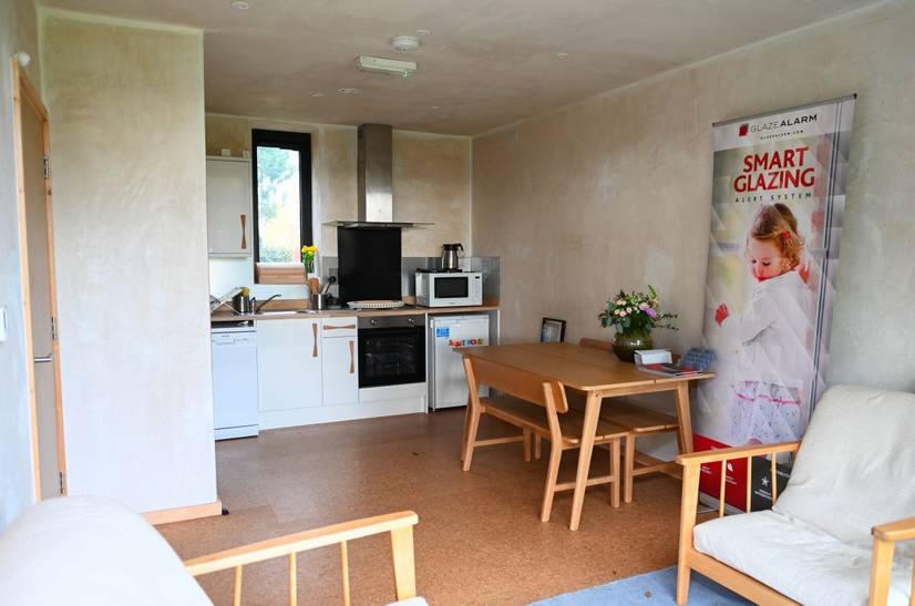 An internal image of the DigiTech Smart House. Visible is a living room and kitchen space including chairs, dining table and kitchen hob and worktop