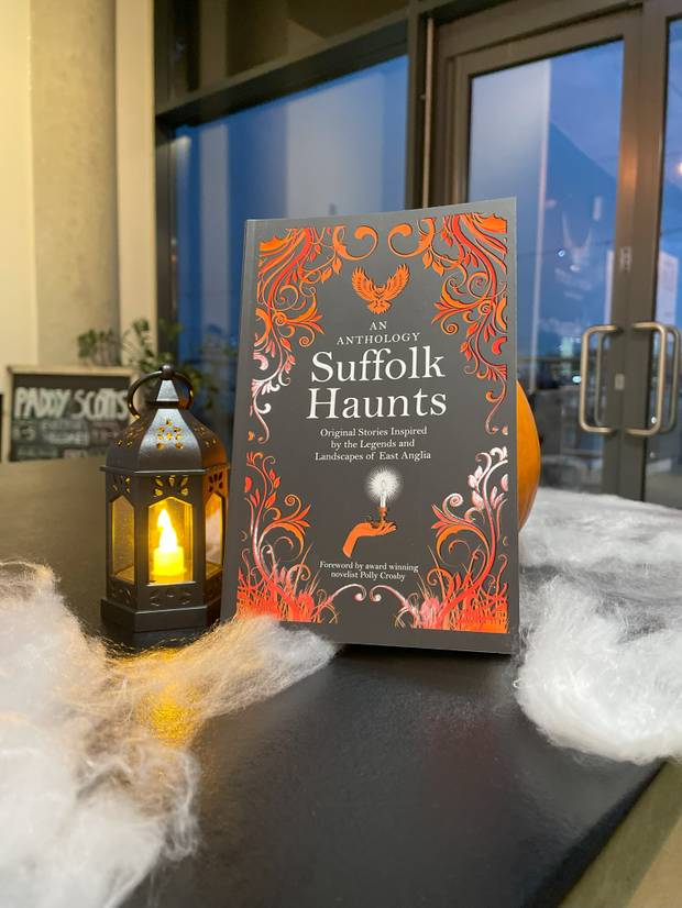 A copy of Suffolk Haunts sitting on a counter top with a Halloween lantern and wisps of spider cobweb around it