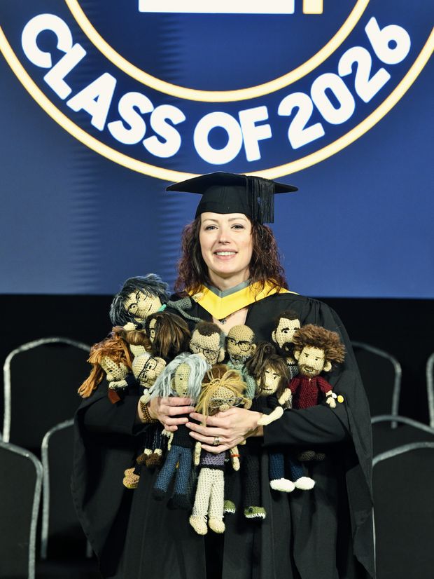Gemma Upson dressed in graduation robes holding all of the caricatures she made