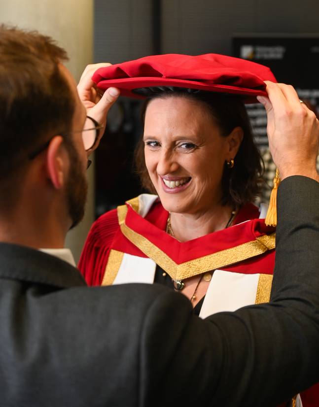 Karen Pickering being helped with her graduation cap