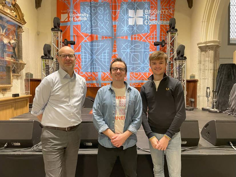 A photo of University of Suffolk COO Tim Greenacre, Brighten the Corners chief executive Joe Bailey and University of Suffolk SU president Lewis Woolston inside the St Stephen's Church venue in Ipswich with the Brighten the Corners logo behind