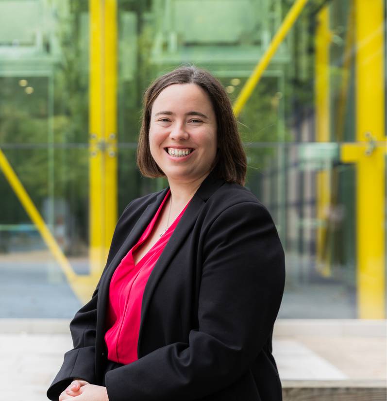 A head and shoulders photo of Dr Georgina Marsh sitting outside the Health and Wellbeing Building, smiling