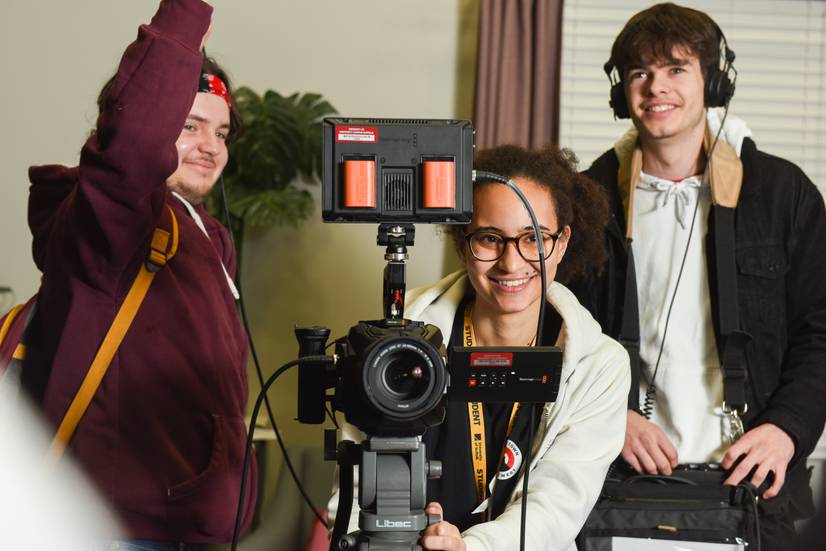 Students standing behind a video camera