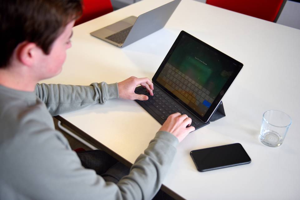 A student sitting at a desk with a tablet
